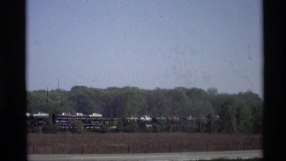 The 1969 Holland, Michigan road view shows freight cars near trees, with the highway crossing the foreground.