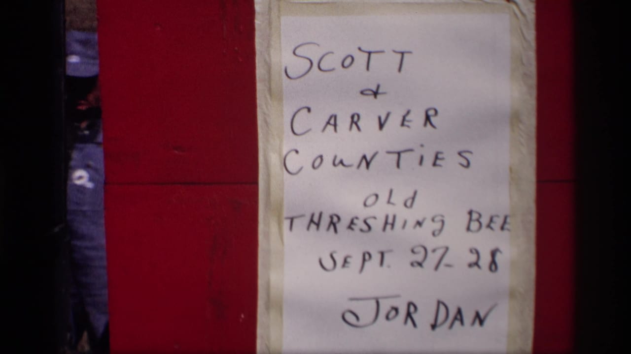 Handwritten Scott and Carver Counties Old Threshing Bee sign taped to a red surface.