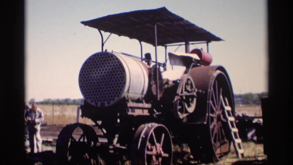 1969 Jordan, Minnesota view of the antique steam-powered farm engine, showing the round perforated boiler face, canopy supports, wheels, and open field beyond.