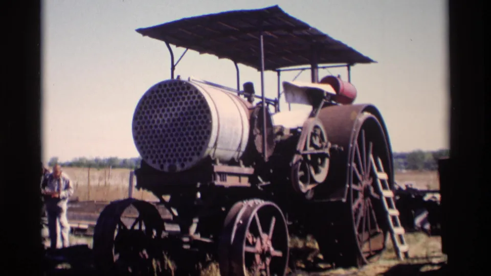 1969 Jordan, Minnesota frame of the steam traction engine from a similar angle, with the canopy, ladder, spoked wheels, and an adult figure visible at left.