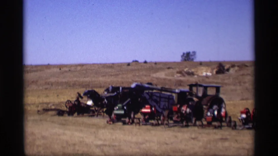 1969 Jordan, Minnesota 8mm frame showing old tractors and farm implements arranged in a sunlit rural field.