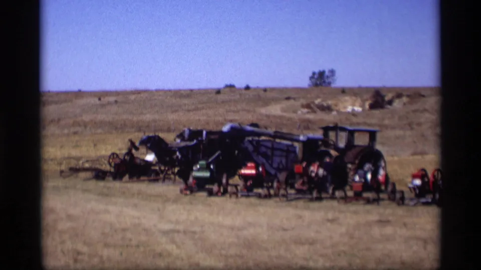 1969 Jordan, Minnesota 8mm frame with visitors near a row of antique tractors and farm equipment outdoors.
