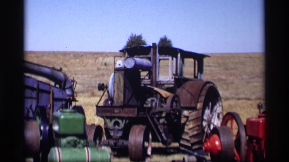 Closer 1969 Jordan, Minnesota home-movie view of a large weathered tractor and nearby vintage farm equipment.