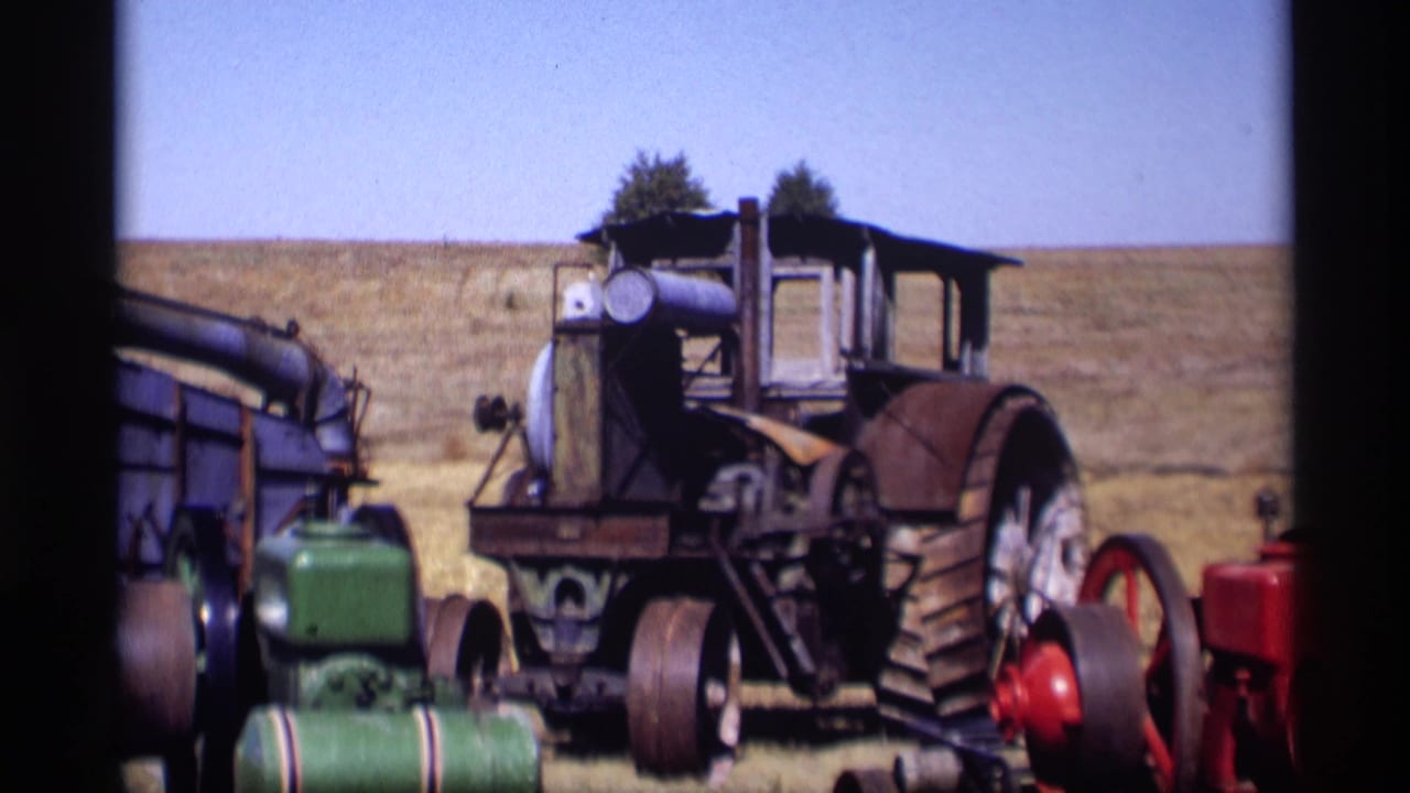 1969 Jordan, Minnesota 8mm frame showing a large old farm tractor with a green engine and red machinery nearby in an open field.
