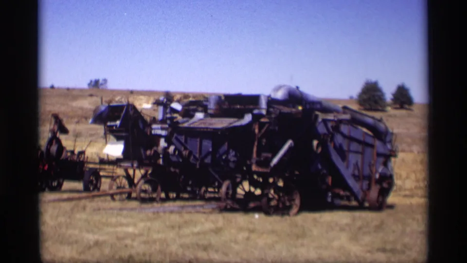 1969 8mm view of blue agricultural equipment and smaller machines resting in a grassy field near Jordan, Minnesota.