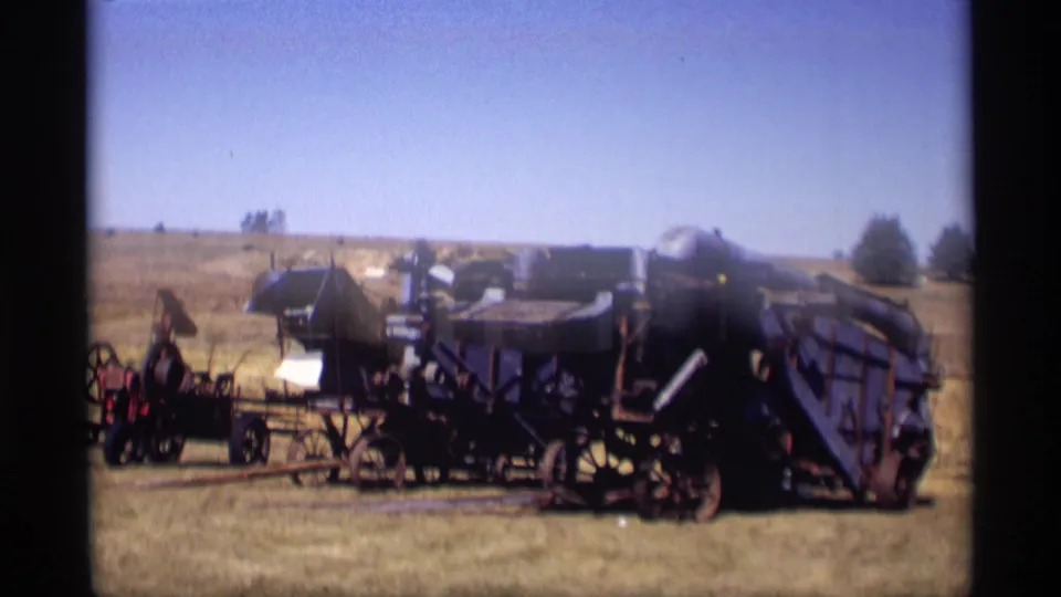 Wide 1969 Jordan, Minnesota home-movie view of dark antique farm machinery and equipment displayed in an open field.