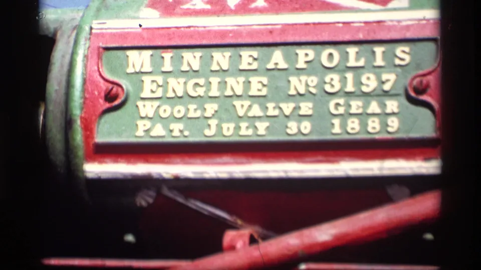 Close 8mm frame of a red and green Minneapolis Engine No. 3197 plate with Woolf Valve Gear patent wording.