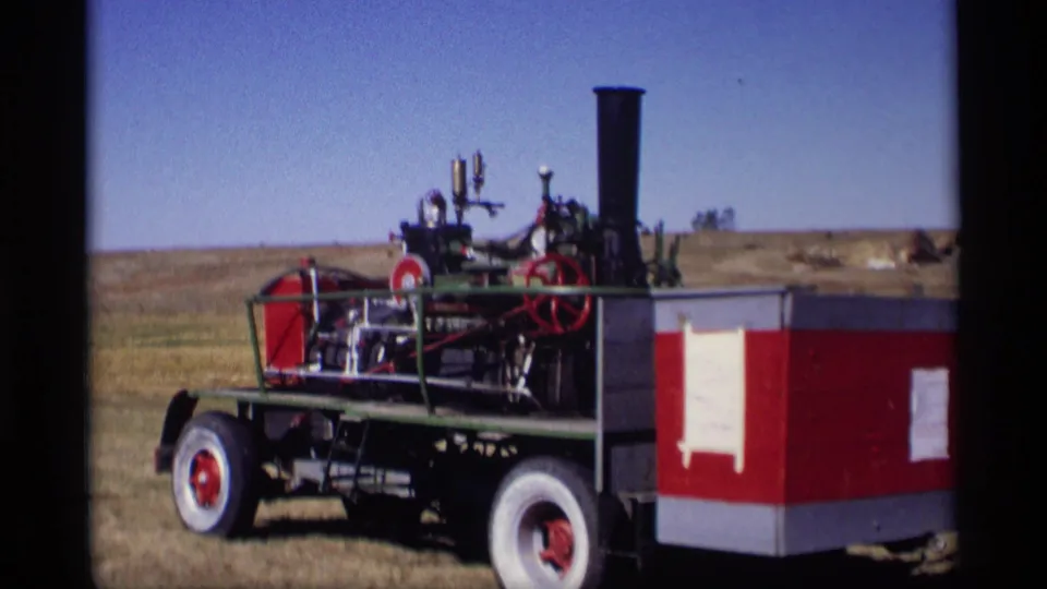 1969 Jordan, Minnesota home-movie frame showing a red and green steam traction engine with smokestack and large wheels in a field.