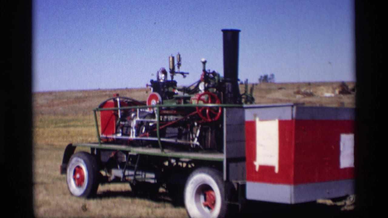 1969 8mm view of a red and white steam tractor with exposed machinery in Jordan, Minnesota.
