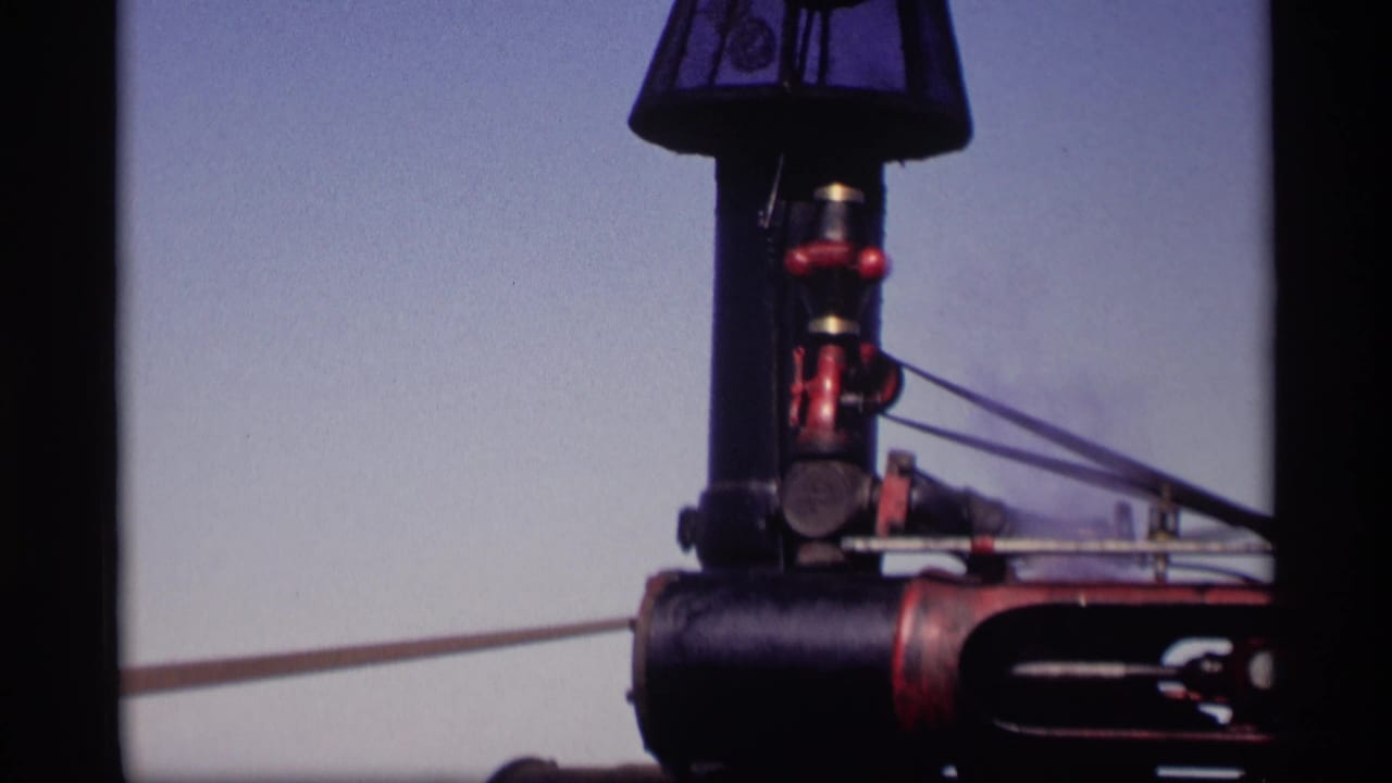 Similar close view of the black and red machinery with rods or belts extending across the frame.