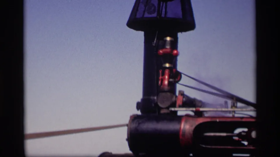 Agricultural machine detail, likely part of a steam-powered or belt-driven setup, filmed in the Jordan, Minnesota 1969 farm scene.