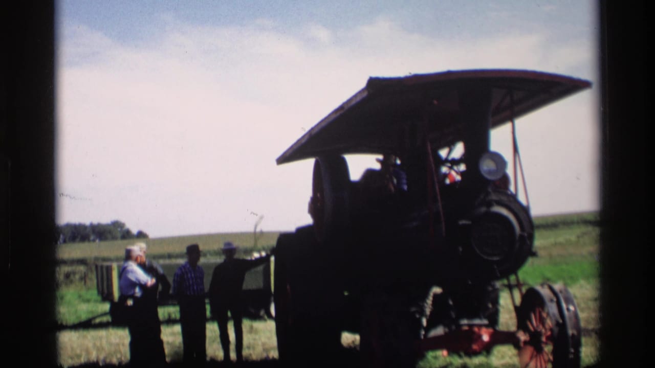 1969 Mabel, Minnesota 8mm frame showing a large steam tractor silhouetted in a field with a small group of people nearby.