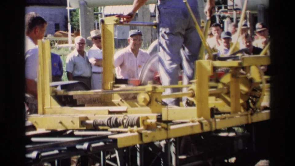 The 1969 Mabel, Minnesota footage shows men watching a yellow industrial cutter while a demonstrator stands near the controls.