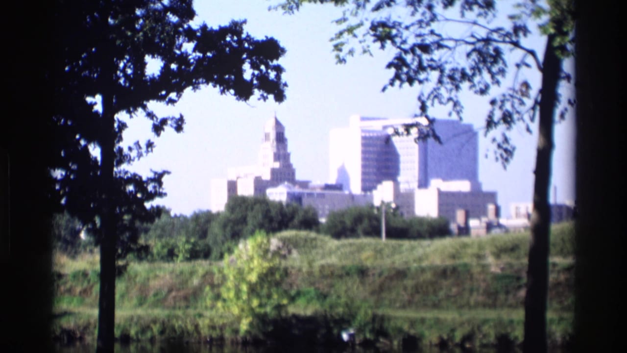 A distant skyline near Mabel, Minnesota appears through tree branches, with low greenery and bright 8mm exposure in the foreground.