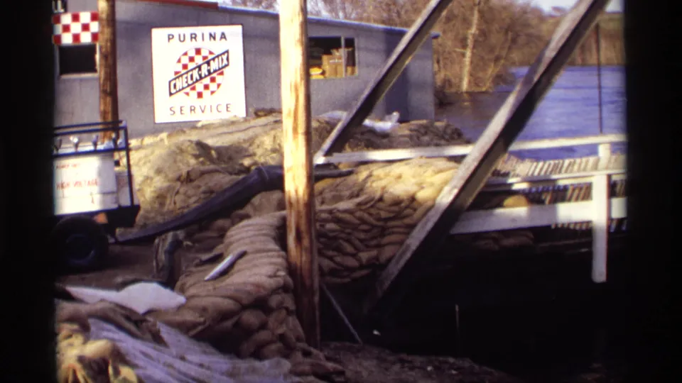1969 Rockford, Minnesota 8mm frame showing the Purina service building area crowded with sandbags and floodwater nearby.