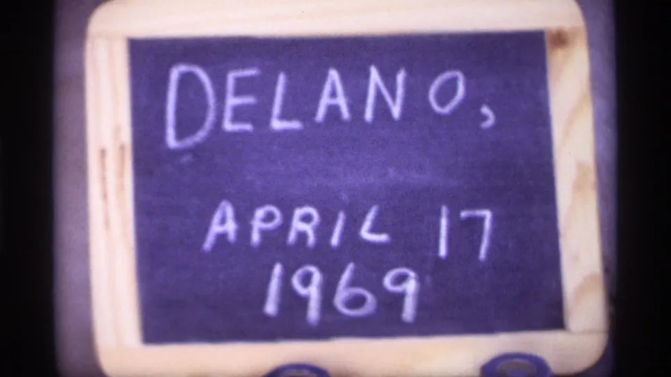 Handwritten chalkboard title card with the place name Delano and the date April 17, 1969, framed closely on 8mm film.