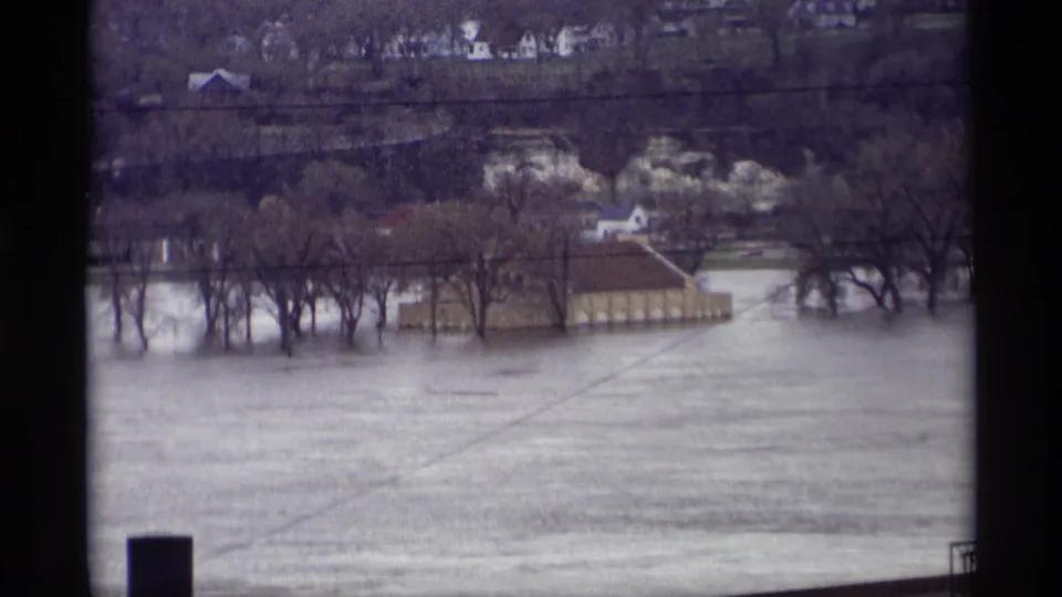 Elevated 1969 Saint Paul flood view with water spread across the riverfront, trees partly surrounded, and houses in the distance.