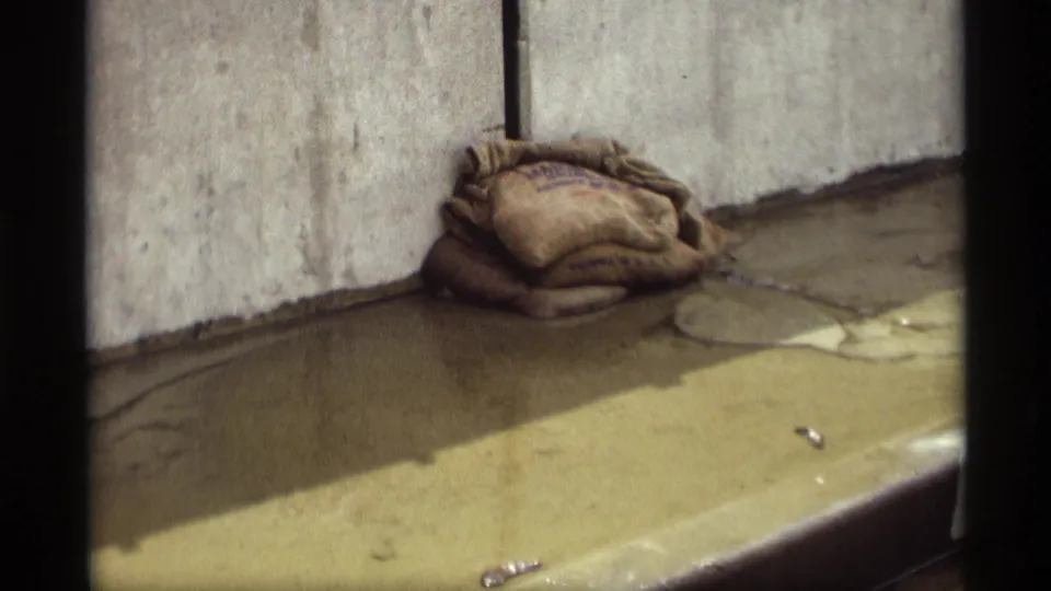 Close 8mm view of sandbags and wet pavement in Saint Paul, Minnesota flood footage from 1969.