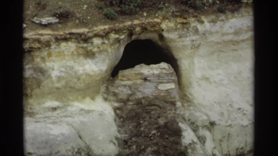 1969 Saint Paul 8mm frame focused on a worn riverbank structure, dark arch, rough stones, and exposed earth.