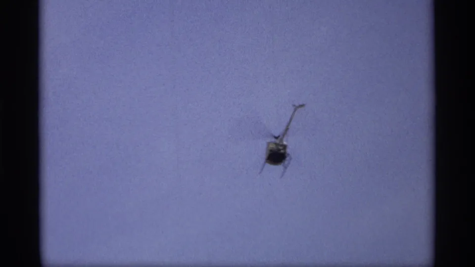 Distant helicopter against a pale blue sky in Saint Paul 1969 home-movie footage following the flood scene.