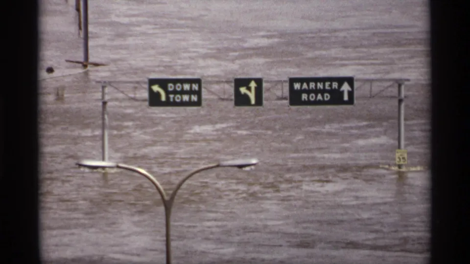 1969 Saint Paul frame showing roadway signs for Down Town and Warner Road above broad muddy floodwater.