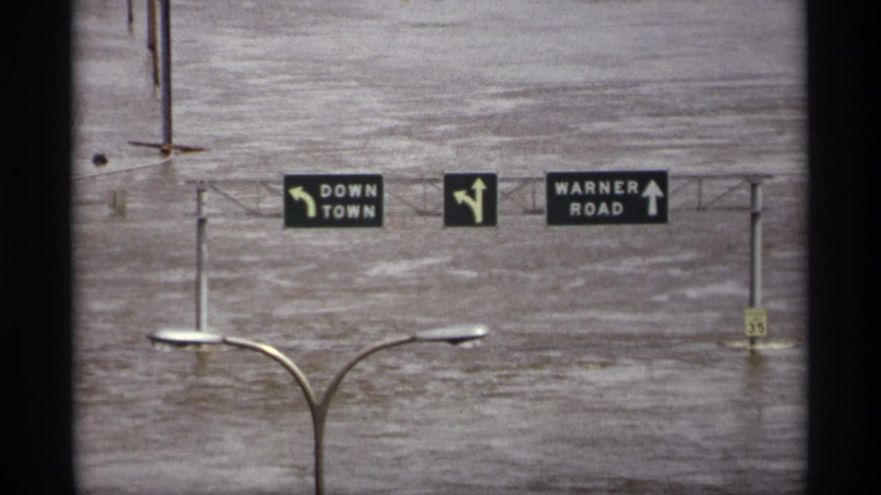 Floodwater beneath overhead signs for downtown and Warner Road.