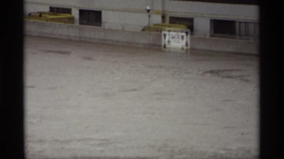 High water in Saint Paul appears to churn below a concrete barrier, with a partially obscured marker above the flood line.