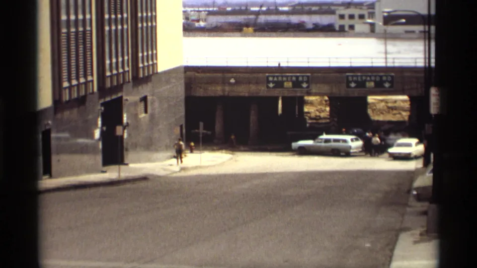 1969 Saint Paul underpass scene shows Warner Rd and Shepard Rd signage, parked 1960s cars, pedestrians, and floodwater beyond.
