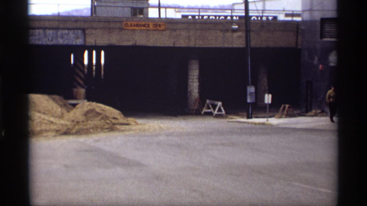 1969 Saint Paul street view showing a concrete underpass, clearance sign, sand piles, tunnel entrances, and street signs from a home-movie angle.