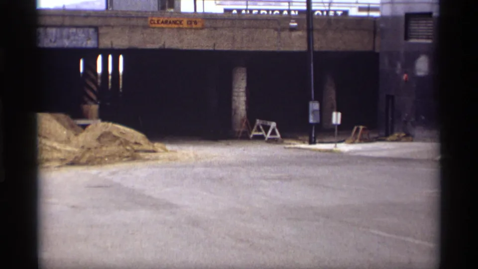 1969 Saint Paul underpass view with sand piles, clearance signs, street poles, and a person walking near the right side of the frame.