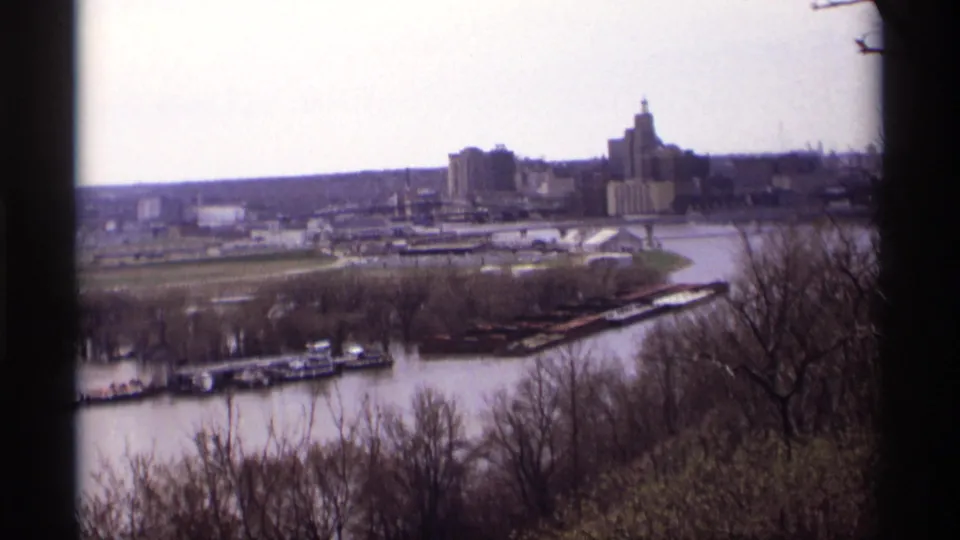 1969 Saint Paul skyline and Mississippi River panorama with boats and bare foreground trees.