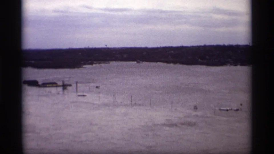 1969 Saint Paul 8mm frame showing a flooded river panorama with small boats, posts, and a low distant shoreline.