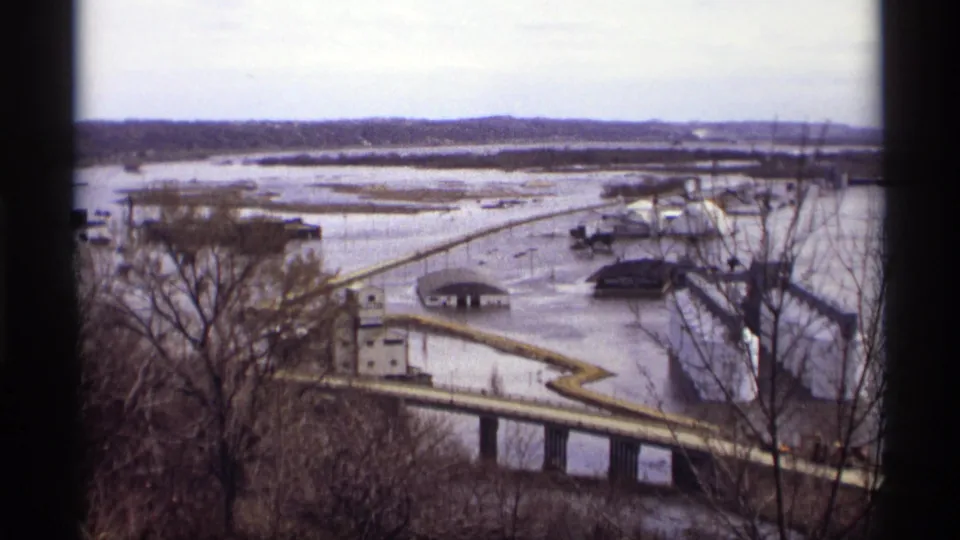 Saint Paul flood scene on 8mm film, with water surrounding a bridge approach and nearby structures in 1969 footage.