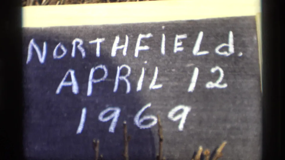 Final 8mm frame of the Northfield, April 12, 1969 chalkboard card, with dark borders, grain, and lower-edge branches visible.