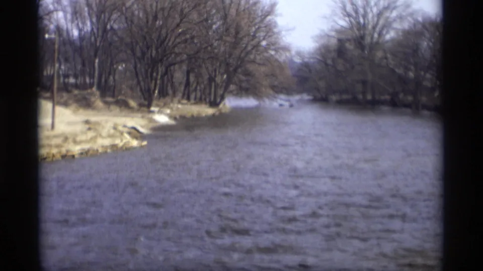 Wide 1969 8mm view of a river running between leafless wooded banks in Savage, Minnesota.