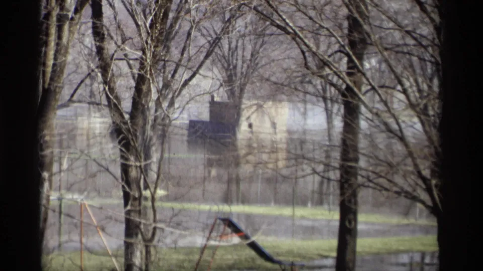 1969 Savage, Minnesota 8mm frame showing floodwater among bare trees, a distant building, and partly submerged playground equipment.