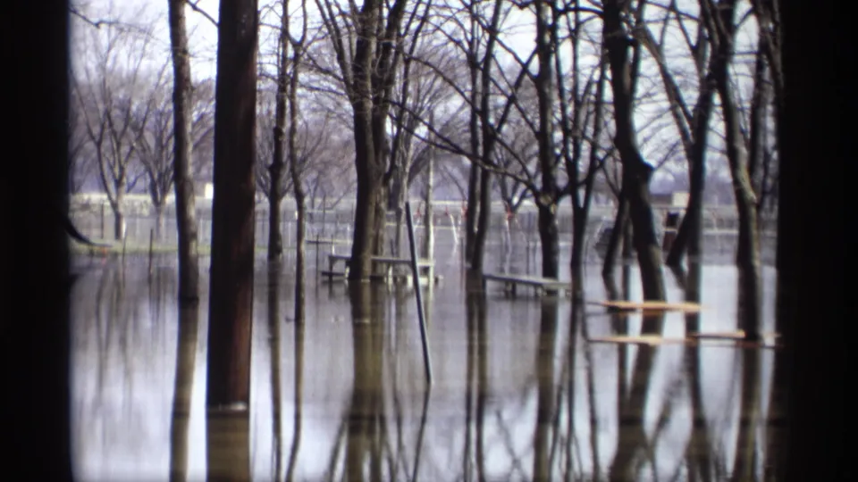 1969 Savage, Minnesota 8mm view of floodwater through bare trees, with benches or picnic tables standing partly underwater.