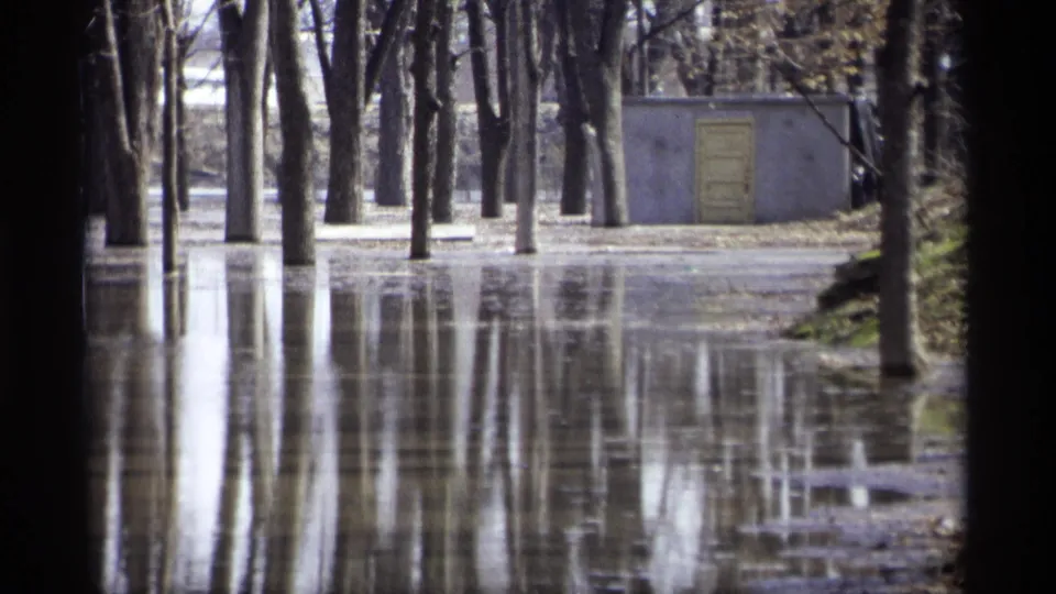 1969 Savage, Minnesota 8mm view of a flooded wooded area with tree reflections and a small concrete building in the background.