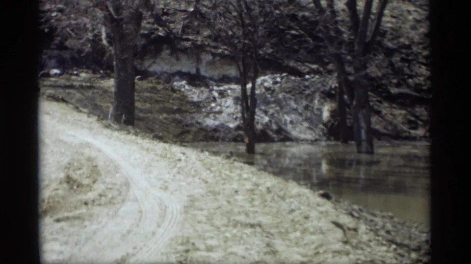 1969 Savage, Minnesota 8mm still showing floodwater around roadside trees and a dirt track along the raised bank.