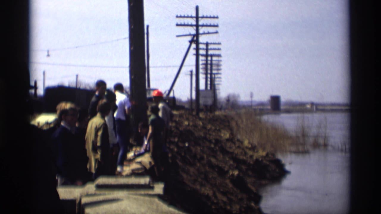 1969 Savage, Minnesota footage shows workers near concrete sections along a railroad embankment beside water and utility poles.