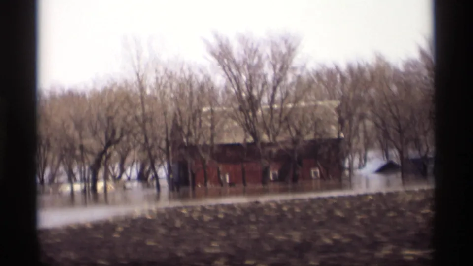 Savage, Minnesota flood footage frame showing a red outbuilding near trees, with water pooled across the background.