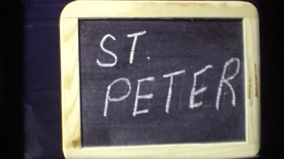 8mm frame of a small chalkboard title card reading ST. PETER, used as a home-movie location marker.