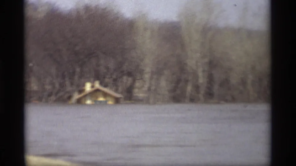 1969 Savage, Minnesota flood scene with a small riverside or lakeside building partly surrounded by high water and winter-bare trees.
