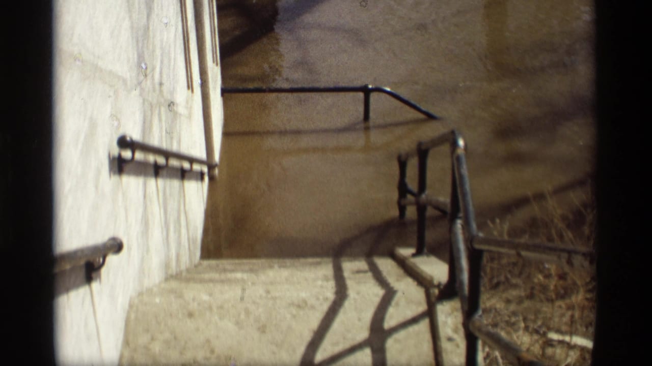 Concrete stairwell with metal handrails above brown floodwater.