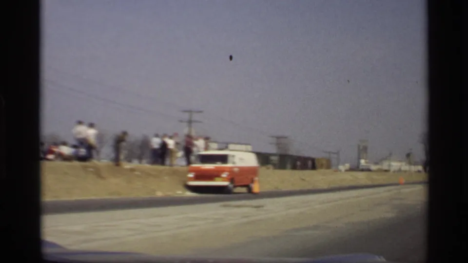 End of the moving-car pass shows the red and white van near the road and people gathered along the embankment in Savage, Minnesota.