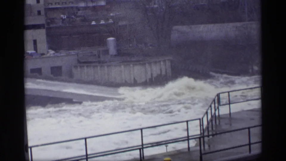 Faded 8mm footage frame of foaming river current near a concrete spillway in 1969 Savage, Minnesota.