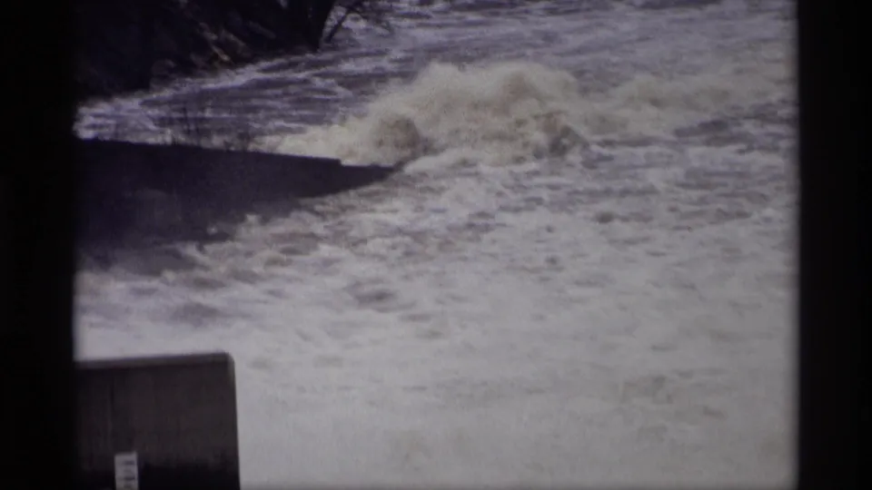 1969 Savage, Minnesota 8mm frame with a breaking wave and white foam moving across turbulent river water.
