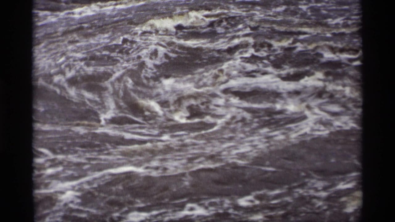 Foamy water currents fill the frame within dark 8mm film borders.