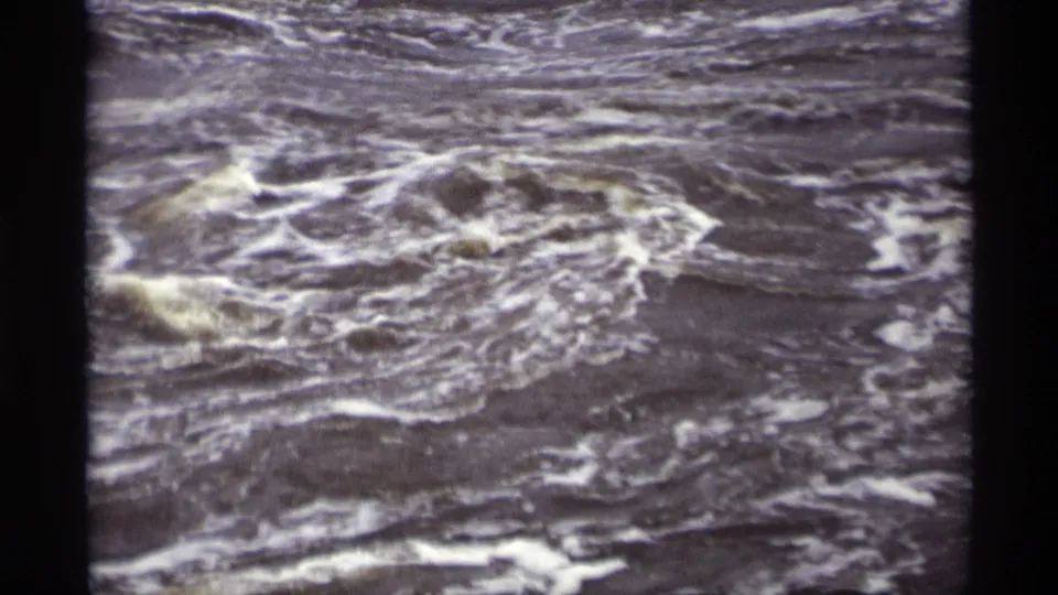 Close 8mm view of turbulent runoff water in Savage, Minnesota, with white foam tracing circular currents.