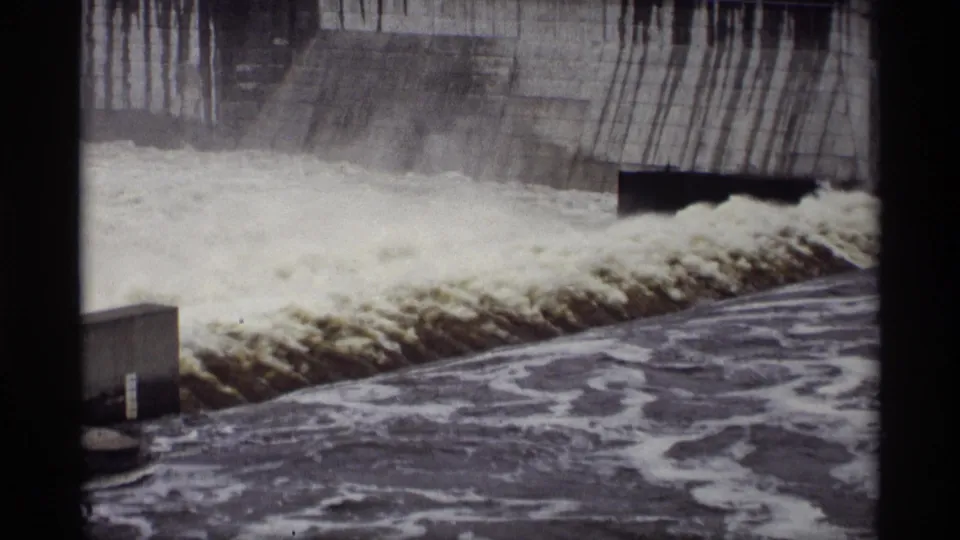 Archival 8mm view of foamy water moving across a concrete spillway, with the Minnesota location supported by clip metadata.